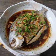 a white bowl filled with fish covered in sauce