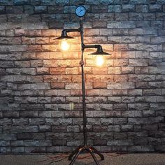 a lamp that is on top of a tripod in front of a brick wall