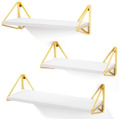 three white shelves with gold brackets on them