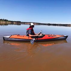 a man in an orange kayak paddling on the water