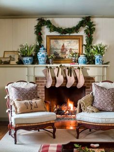 two chairs sitting in front of a fire place with stockings hanging on the mantel