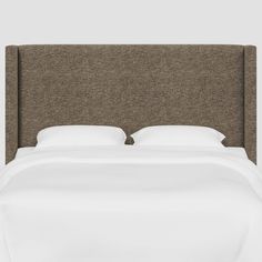 an upholstered headboard with white sheets and pillows