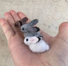 a hand holding a tiny stuffed animal in it's palm