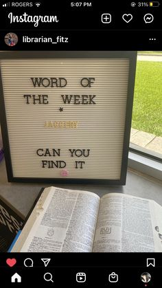 an open book sitting on top of a table next to a sign that says word of the week