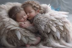 two babies are cuddling together in an angel - like blanket with feathers on it