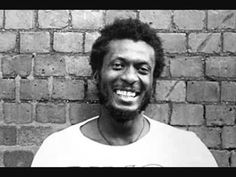 a man smiling in front of a brick wall