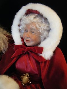 a small child dressed as santa clause with a red cape and white fur on it's head