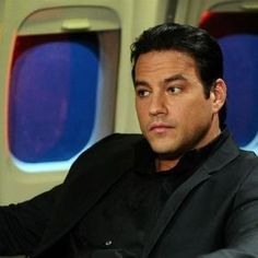 a man sitting in an airplane seat with his hand on the arm and looking off into the distance