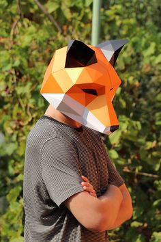 a man wearing an origami fox mask with his arms crossed in front of him