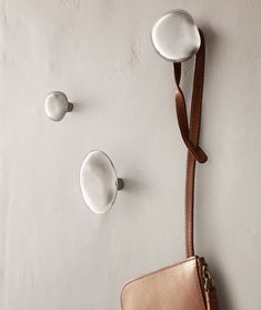 a purse hanging on the wall next to two hooks