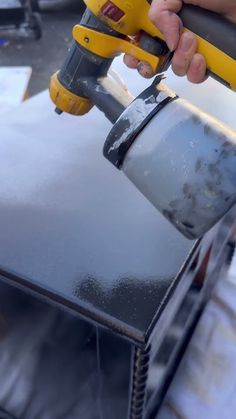 a person using a power drill to paint a metal surface