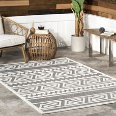 a white and grey area rug on the floor next to a table with a potted plant