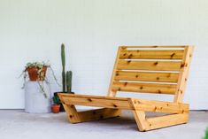 a wooden chair sitting in front of a white brick wall next to a potted plant