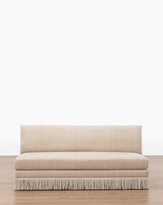 a beige couch sitting on top of a hard wood floor next to a white wall