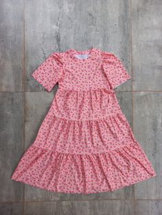 a pink dress with polka dots on it sitting on a tile floor in front of a wall