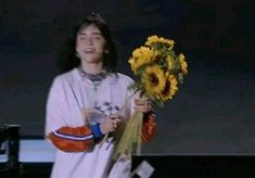 a woman holding a bouquet of sunflowers on stage