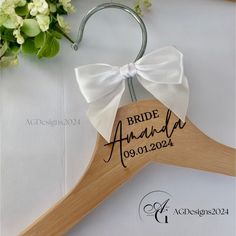 a wooden hanger with a white bow on it and the bride's name