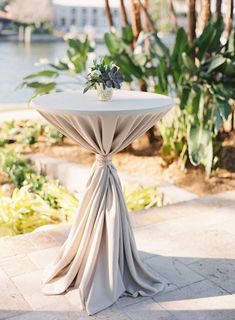 a white table topped with a vase filled with flowers sitting on top of a tiled floor