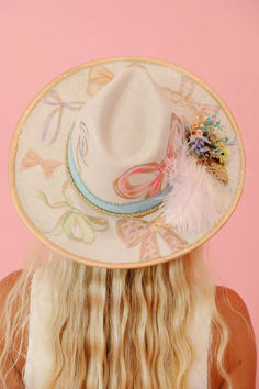 Add some whimsy to your wardrobe with THE CHARLOTTE RANCHER HAT. This cream hat features playful gold accents, pastel painted bows, and a charming blue ribbon band. Adorned with pink and gold feathers and a delightful floral combo, this hat is perfect for those who love a good bow. Hat Bar Party, Painting Outfit, Cute Cowboy Hat, Derby Hats Diy Ideas, Sari Ideas, Rancher Hats, Aesthetic Hats, Leather Burning, Cowgirl Hats Western