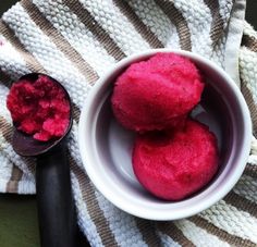 two bowls filled with red colored food on top of a striped towel next to a spoon