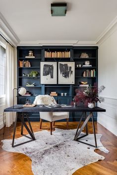 a home office with black bookcases and an area rug on the wooden floor