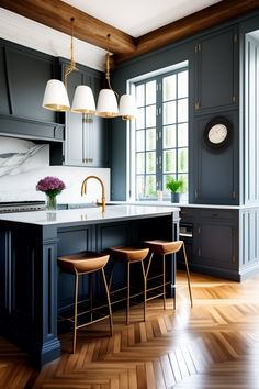 a large kitchen with wooden floors and gray cabinets, white marble counter tops and gold accents