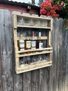 an old wooden shelf with bottles and glasses on the top is hanging from a fence