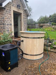 a large wooden barrel sitting next to a brick building with a hose connected to it