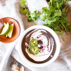 a white bowl filled with food next to a spoon and some cilantros