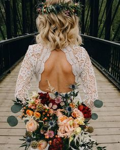 the back of a woman's dress with flowers in her hair, holding a bouquet