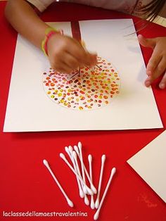 someone is making something out of paper on the table with straws and glue sticks