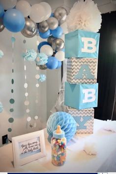 a baby shower party with blue and silver decorations, balloons and gift boxes on the table