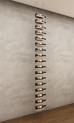 a tall wine rack with many bottles hanging from it's sides in an empty room