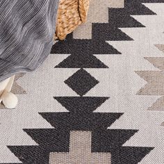 a black and white rug with an arrow pattern on it, next to a wicker basket