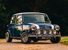 an old blue and white car is parked on the side of the road in front of some trees