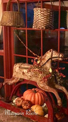 a wooden sleigh with pumpkins and gourds in front of a window