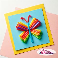 a colorful butterfly made out of plastic straws on top of a blue and yellow card