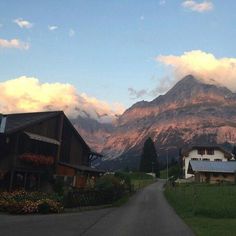 the mountains are covered in clouds and some houses on the side of the road,