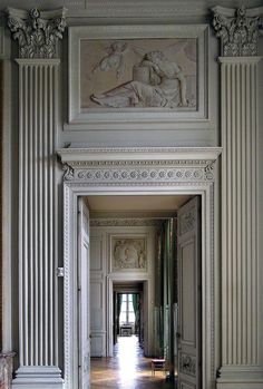 an open door leading to a hallway with statues on the walls