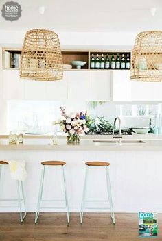 three stools in front of a counter with flowers and bottles on the top shelf