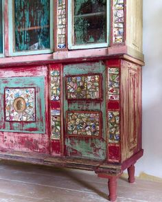 an old dresser painted in red, green and gold with glass inserts on the doors