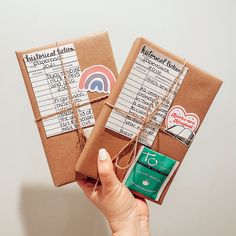 two brown packages with stickers on them are held by a woman's hand