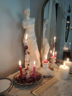 a table topped with candles next to a mirror and a statue on top of it