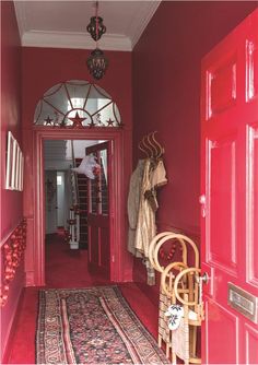 a hallway with red walls and rugs on the floor