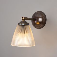 an old fashioned wall light with a glass shade on the bulb and arm, against a gray background