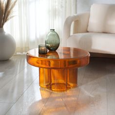 a glass table sitting on top of a hard wood floor next to a white couch