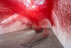 an art installation with red trees in the center and white walls on either side of it