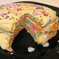 a cake with white frosting and colorful sprinkles on a black plate