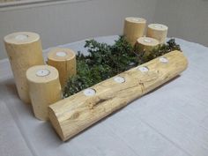 a wooden log with candles and moss in it sitting on a white tablecloth covered table