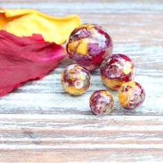 some red and yellow fruit sitting on top of a wooden table next to an orange leaf